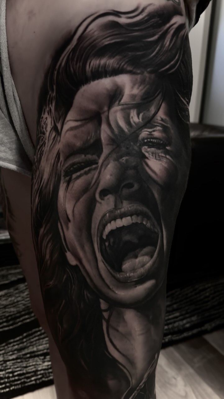 Hyper-detailed grayscale screaming portrait on upper arm.