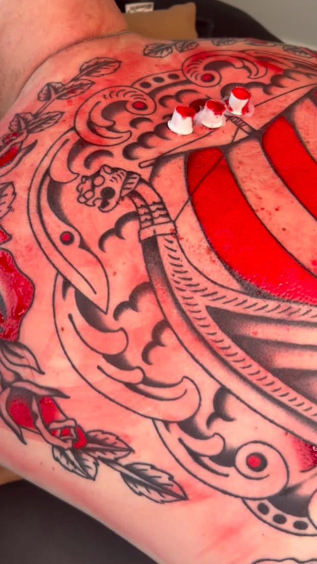 Bold traditional tattoo with skulls and floral scrolls