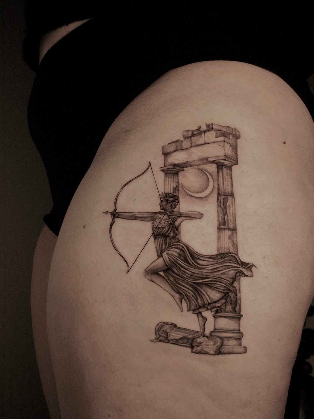 Artemis with a bow beside ancient ruin columns