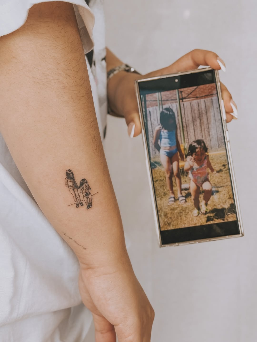 Delicate fine-line duo of children on forearm