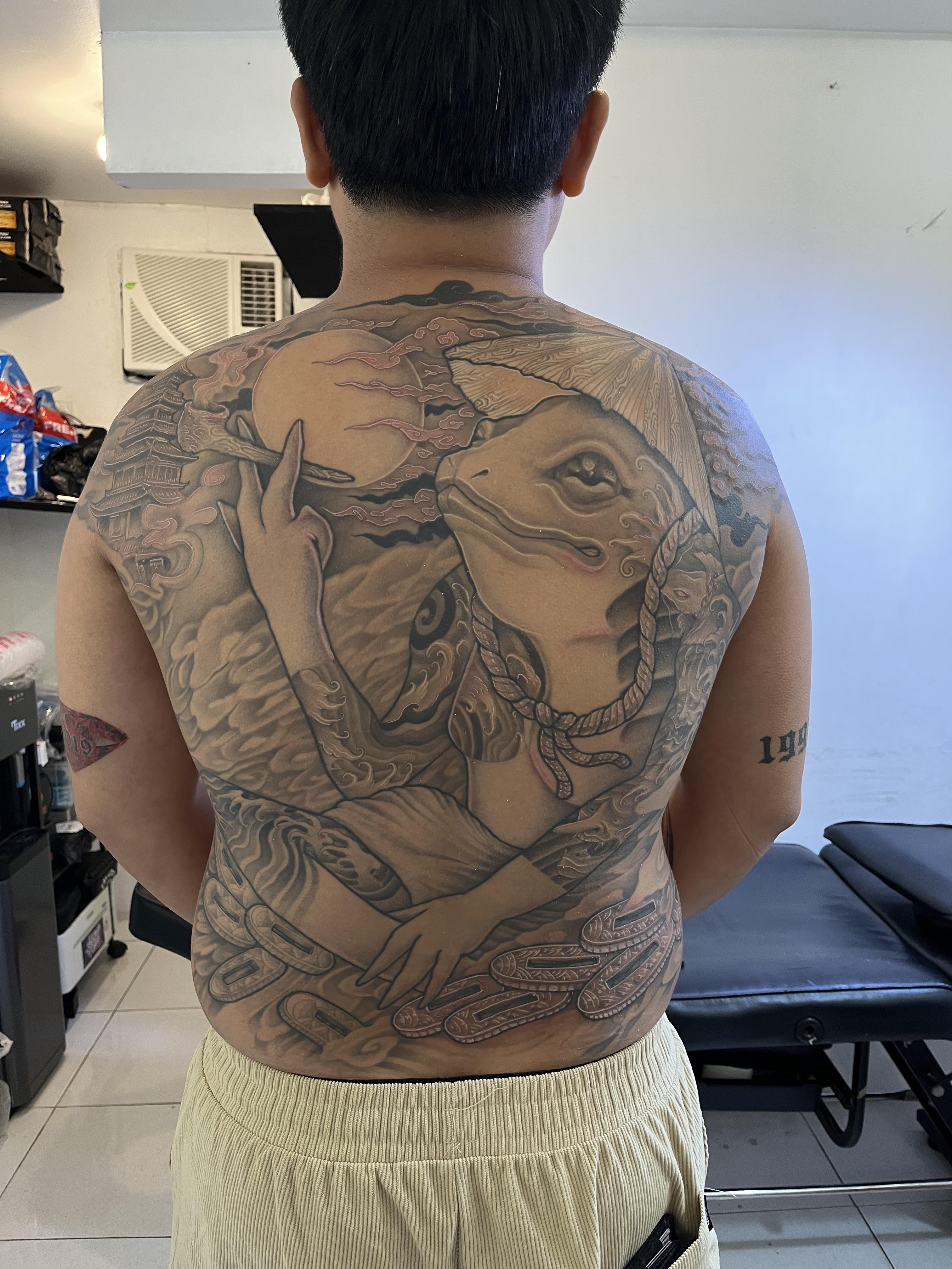 Massive black-and-gray Japanese backpiece with koi-like creature and waves.