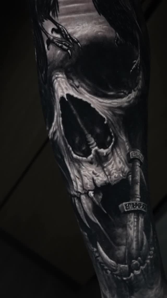 Nordic-themed black-and-gray skull with sword on the forearm