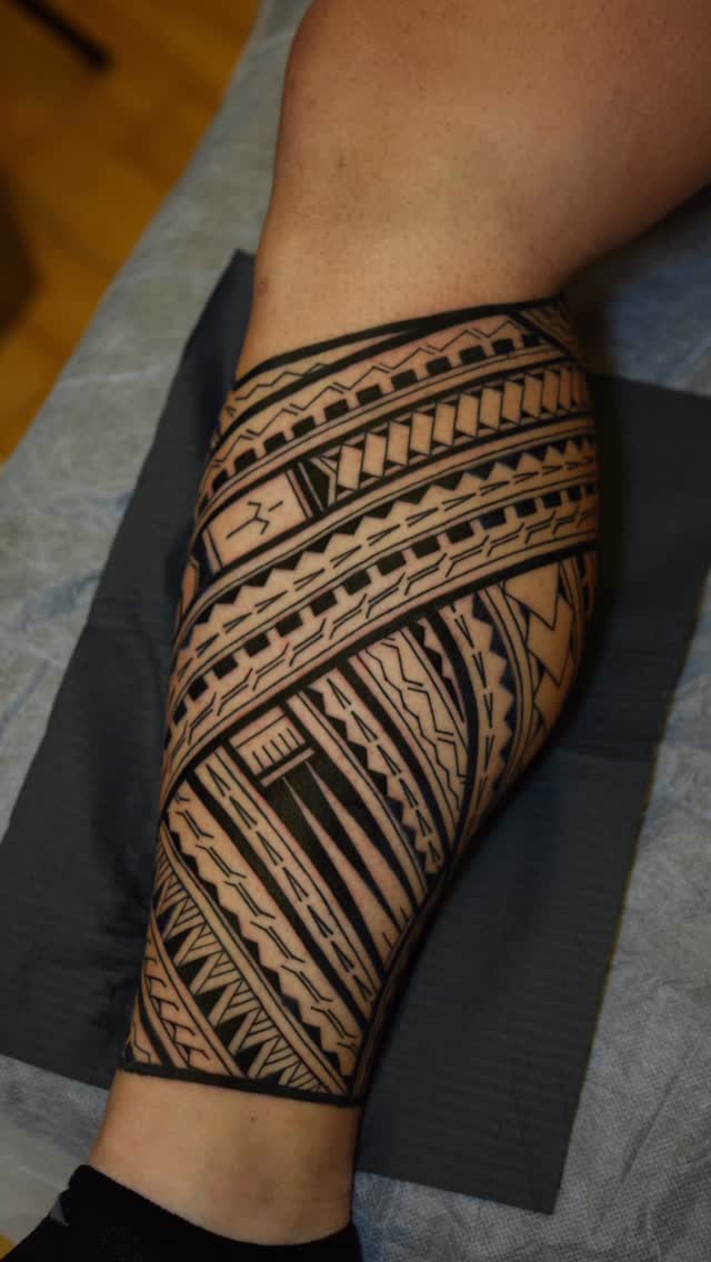 Bold black tribal geometry wraps calf in crisp lines.