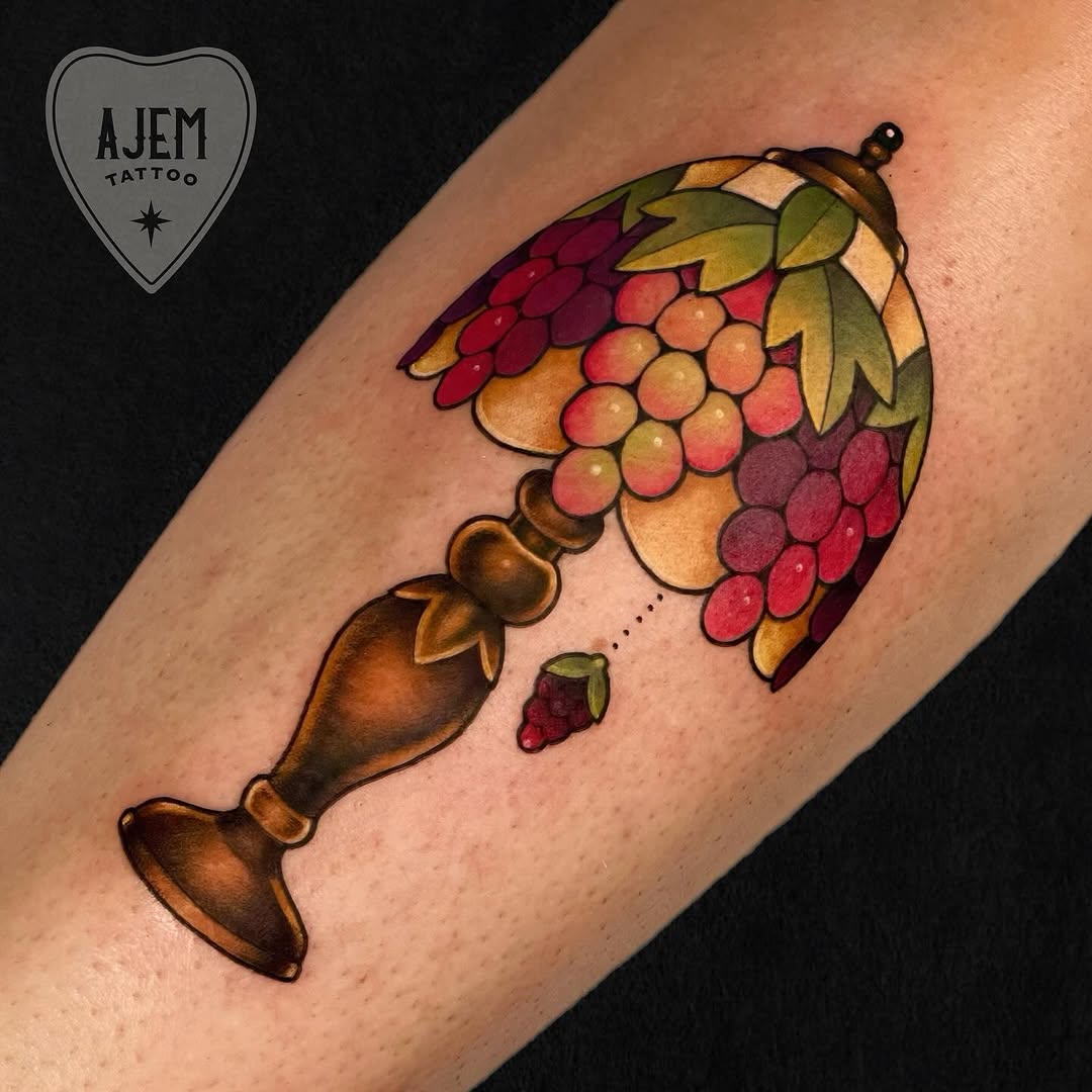 Vivid stained-glass grape lamp tattoo with bold outlines