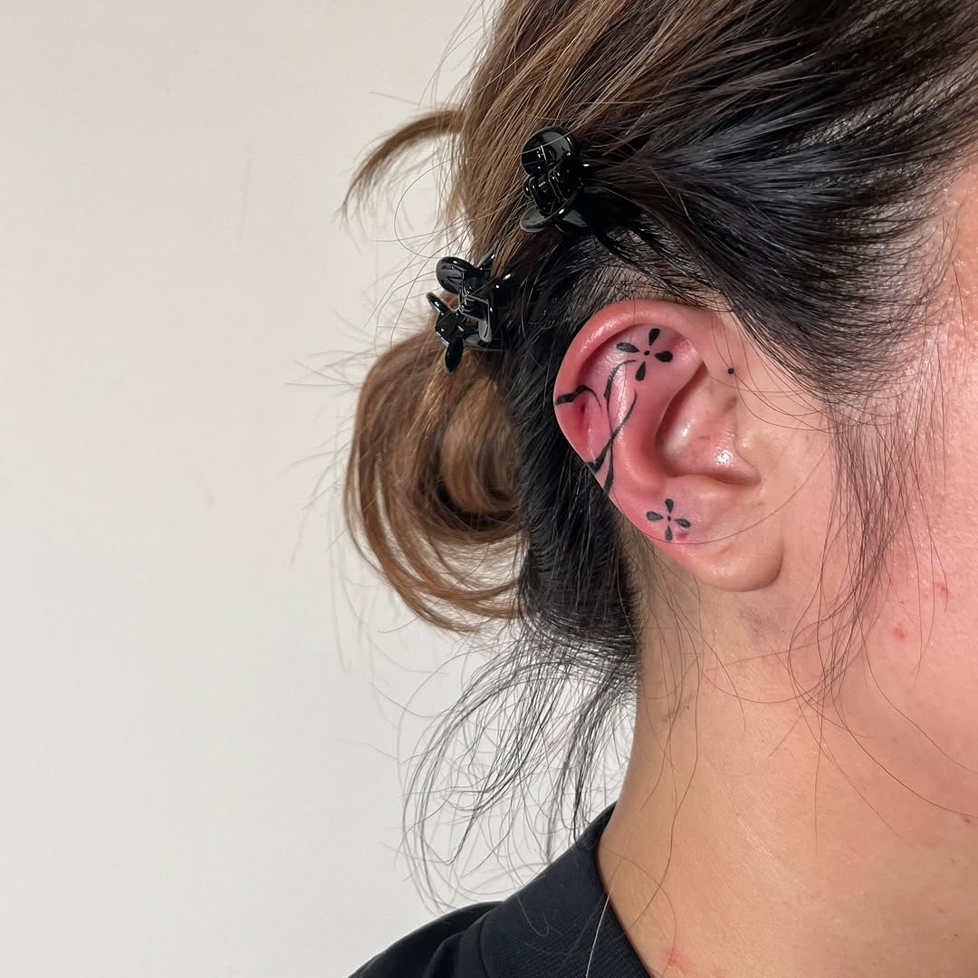 Delicate black floral linework wrapping the ear.