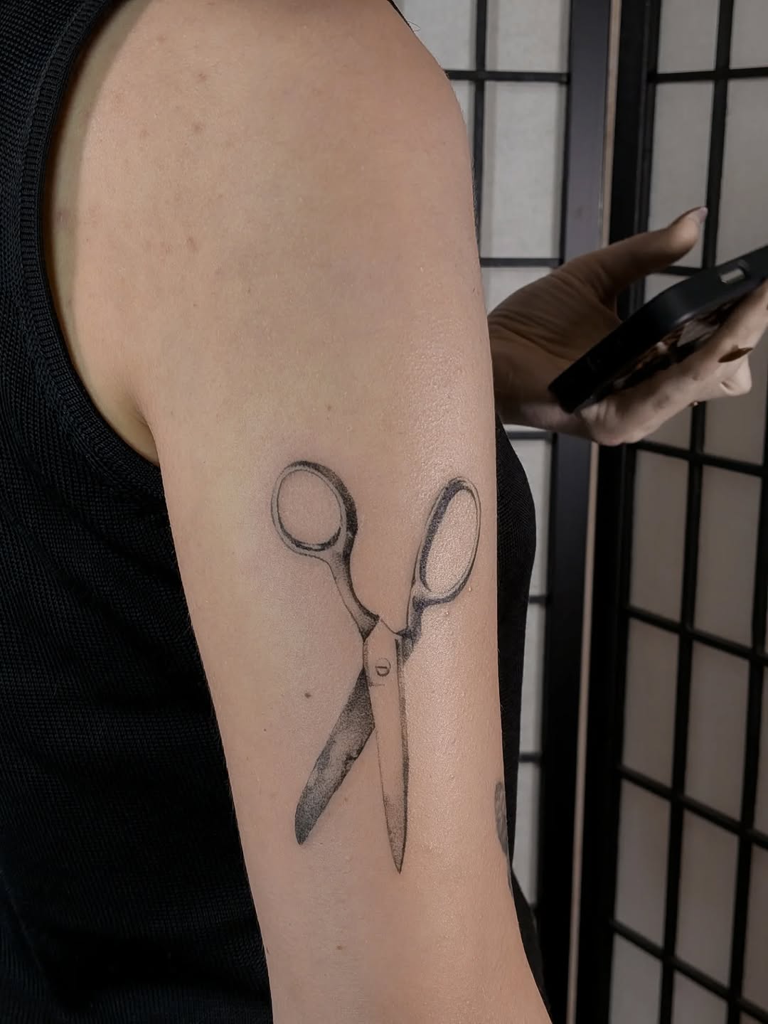 Minimalist blackline scissors tattoo with subtle shading.