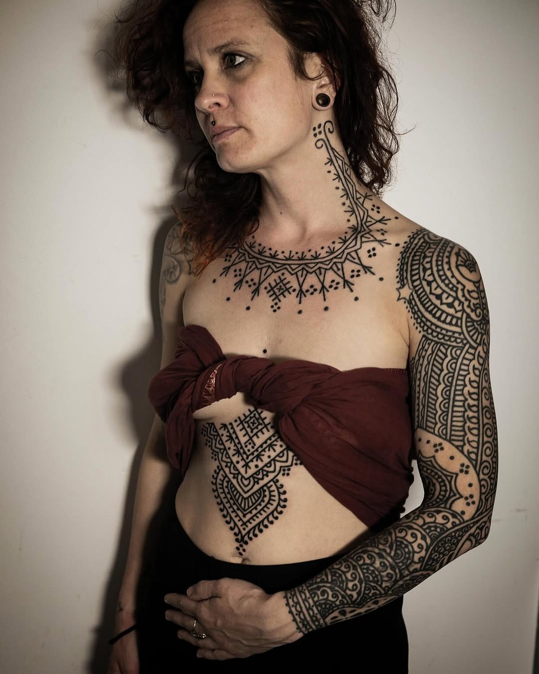 Intricate blackwork geometric bodysuit across neck, chest, arm