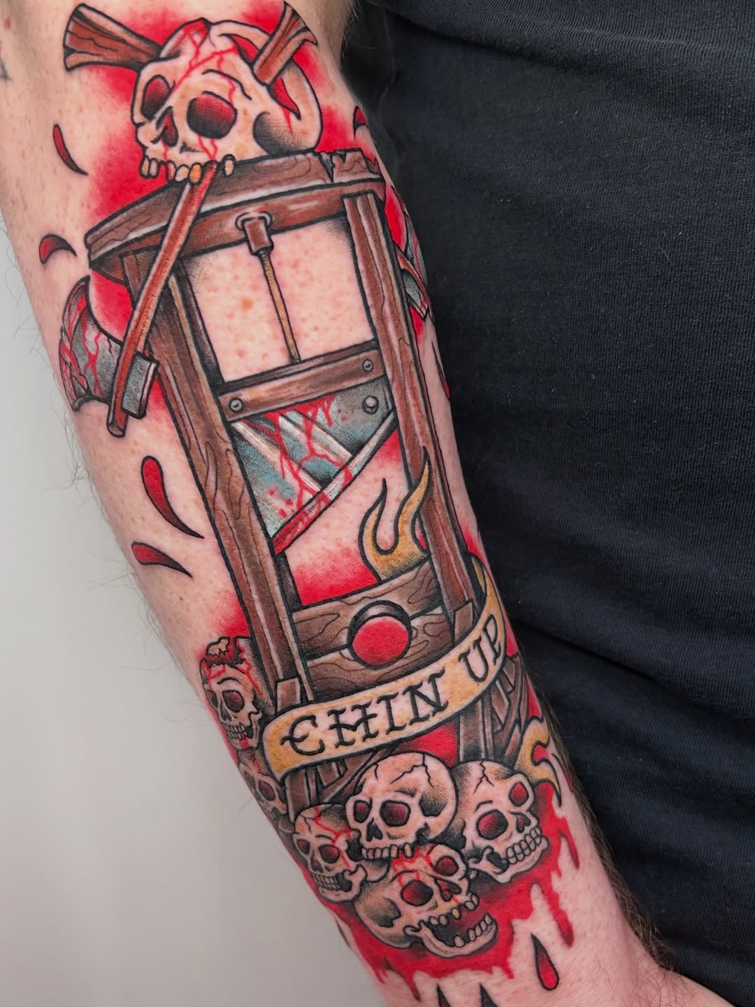 Bold neo-traditional guillotine with snarling skulls, crimson background