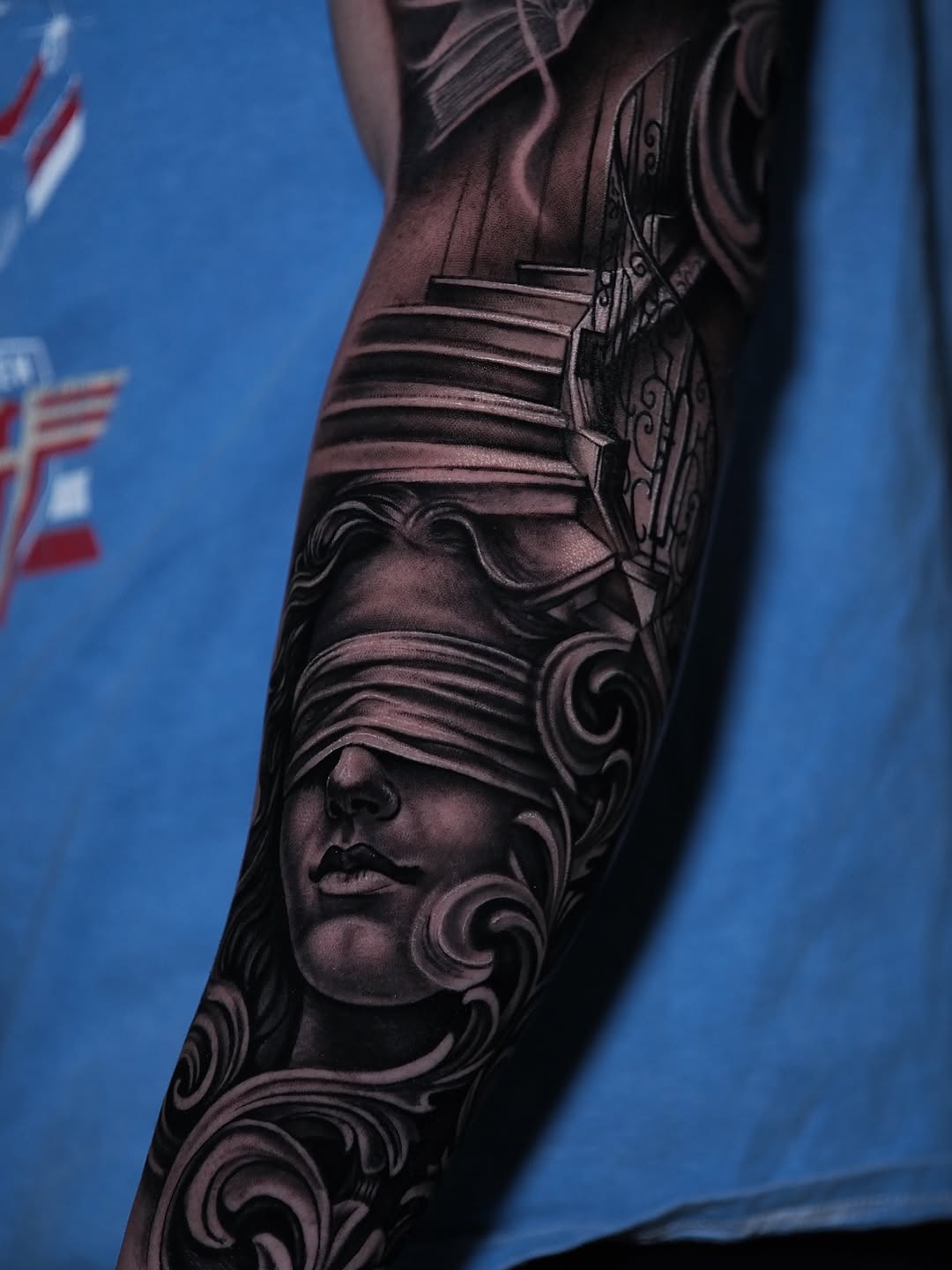 Dramatic black-and-gray portrait with flowing scrollwork.