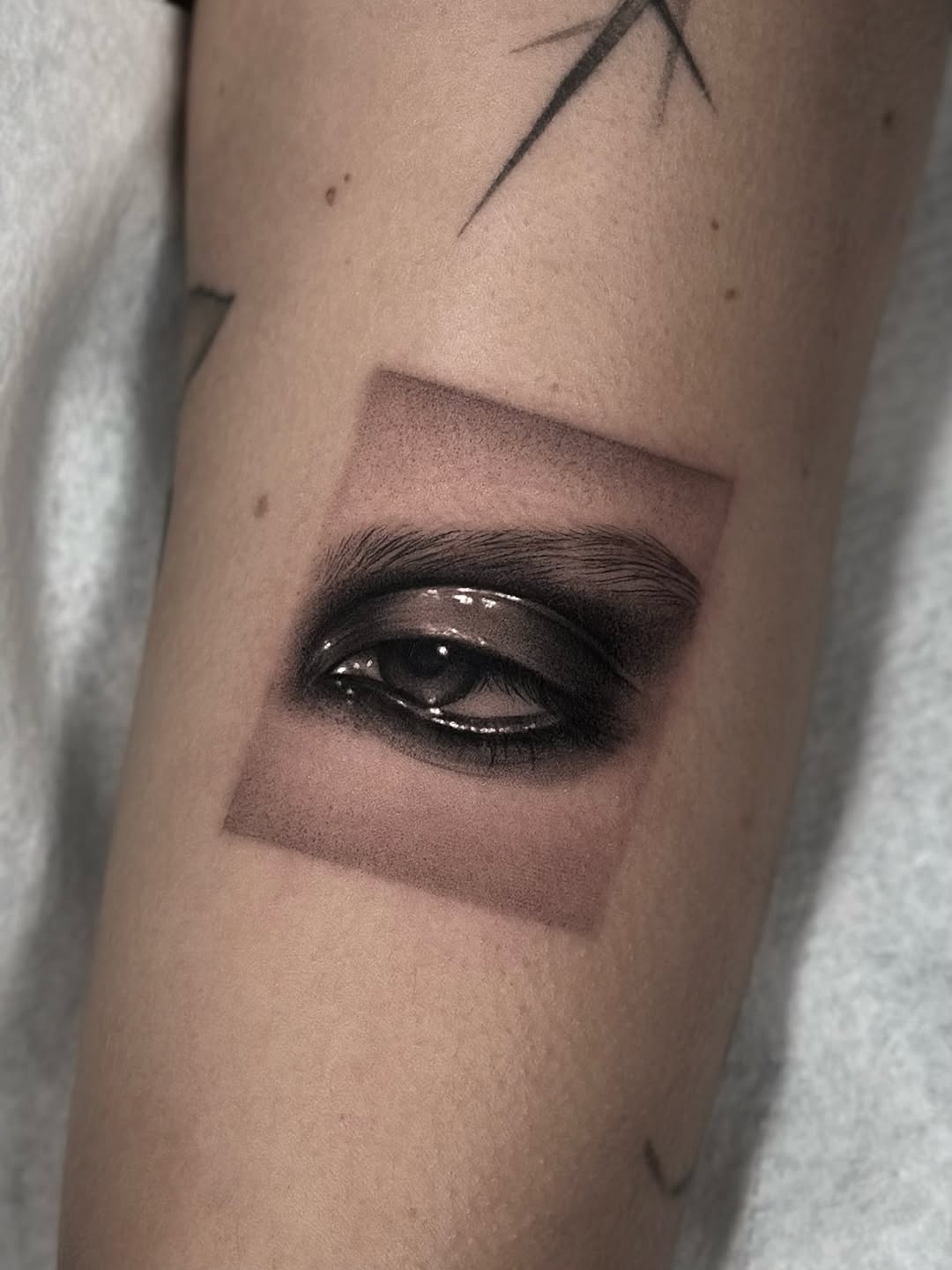 Hyper-realistic eye framed by bold square shading.