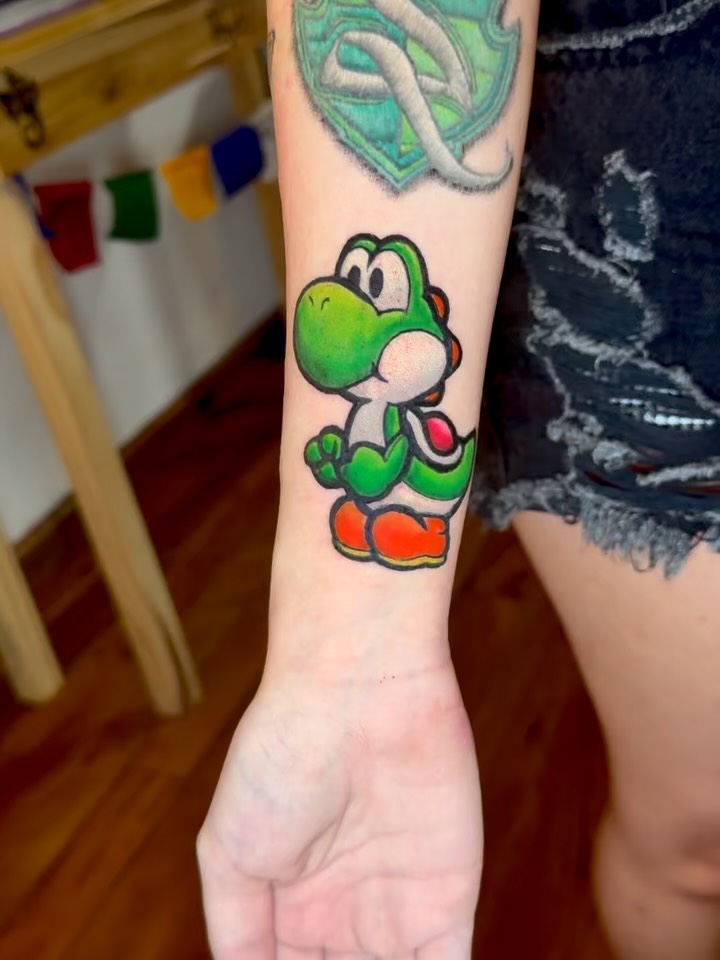 Bold cartoon Yoshi on forearm, neon-green expressiveness
