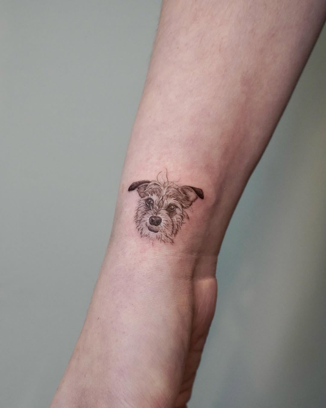 Delicate fine-line dog portrait on the wrist.