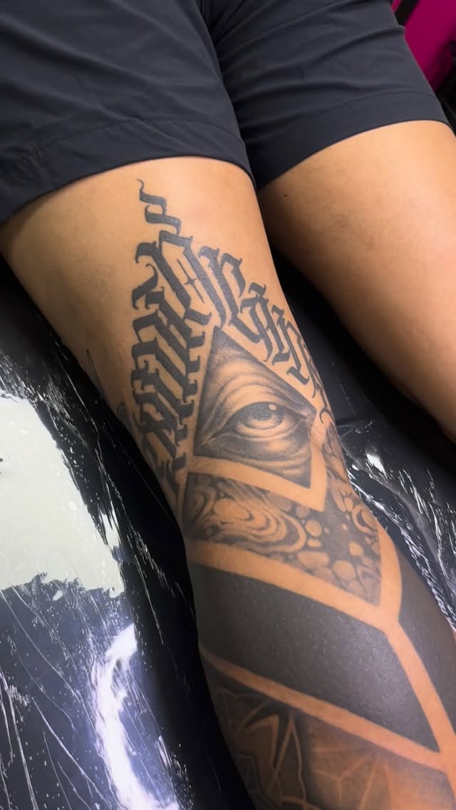 Geometric blackwork leg piece featuring an eye inside a triangle.