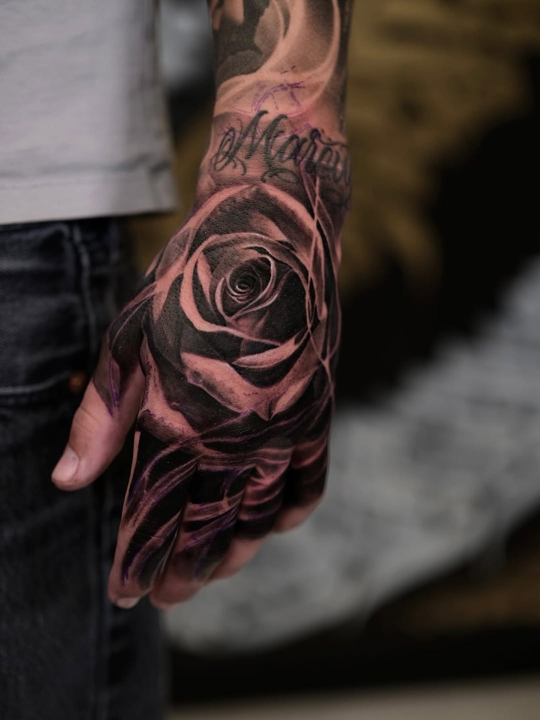 Hyper-detailed black-and-gray rose wraps the hand.