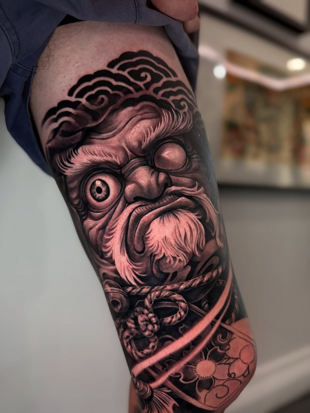 Bold black-and-gray Daruma portrait with swirling waves