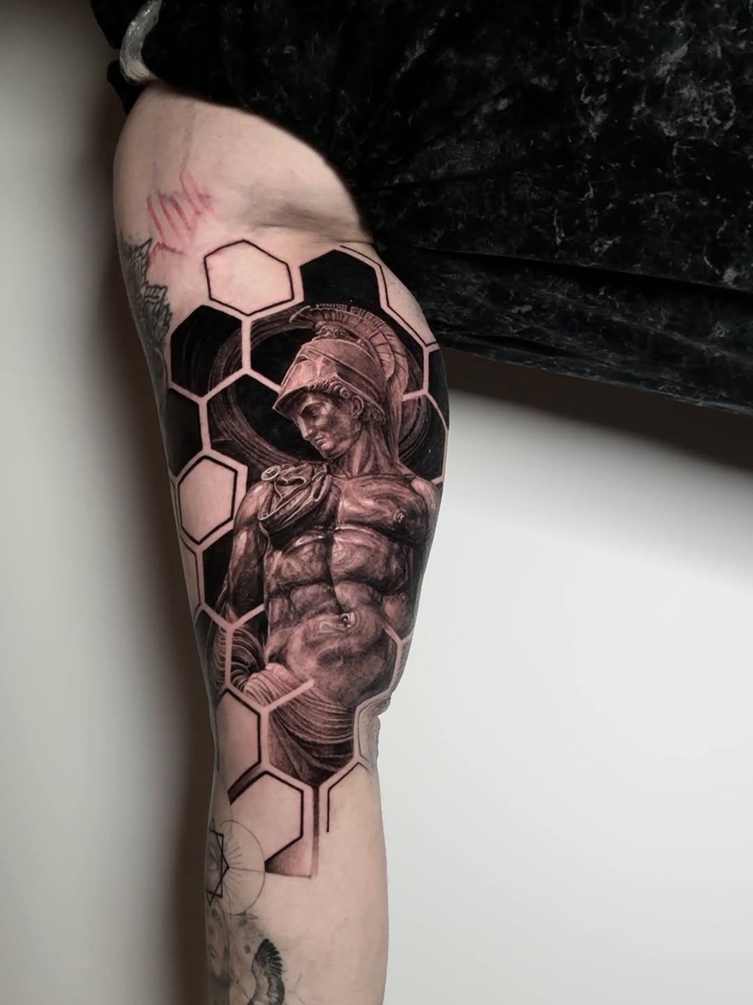 Neo-classical helmeted-warrior in black-and-gray realism with hexagonal honeycomb panels