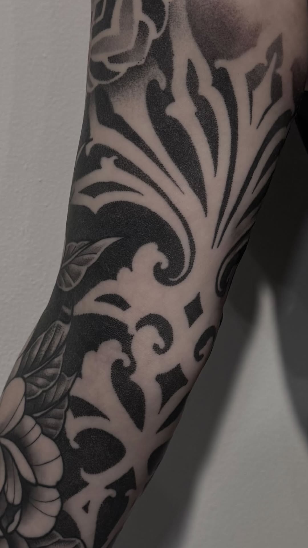 Bold blackwork ornamental floral sleeve with negative-space contrast