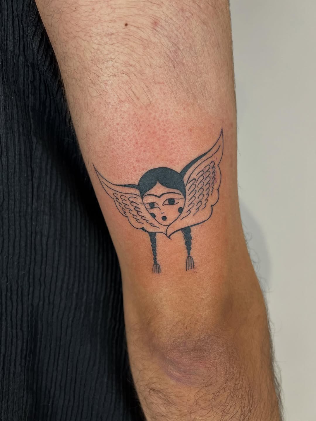 Whimsical black-line angel with braided pigtails.