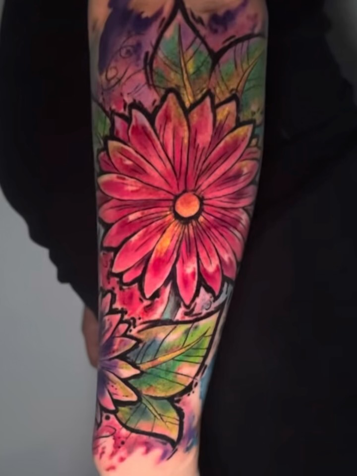 Vibrant watercolor floral forearm tattoo with bold black outlines