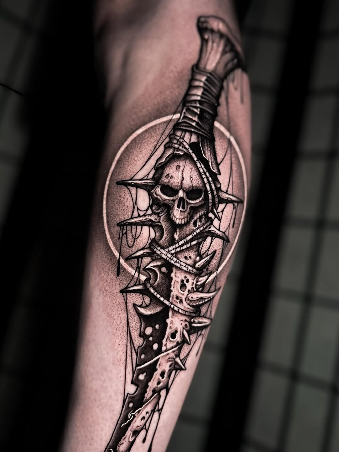 Decaying skull entwined with barbed dagger in blackwork.