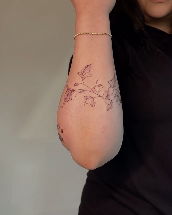 Delicate fine-line floral vine wrapping forearm