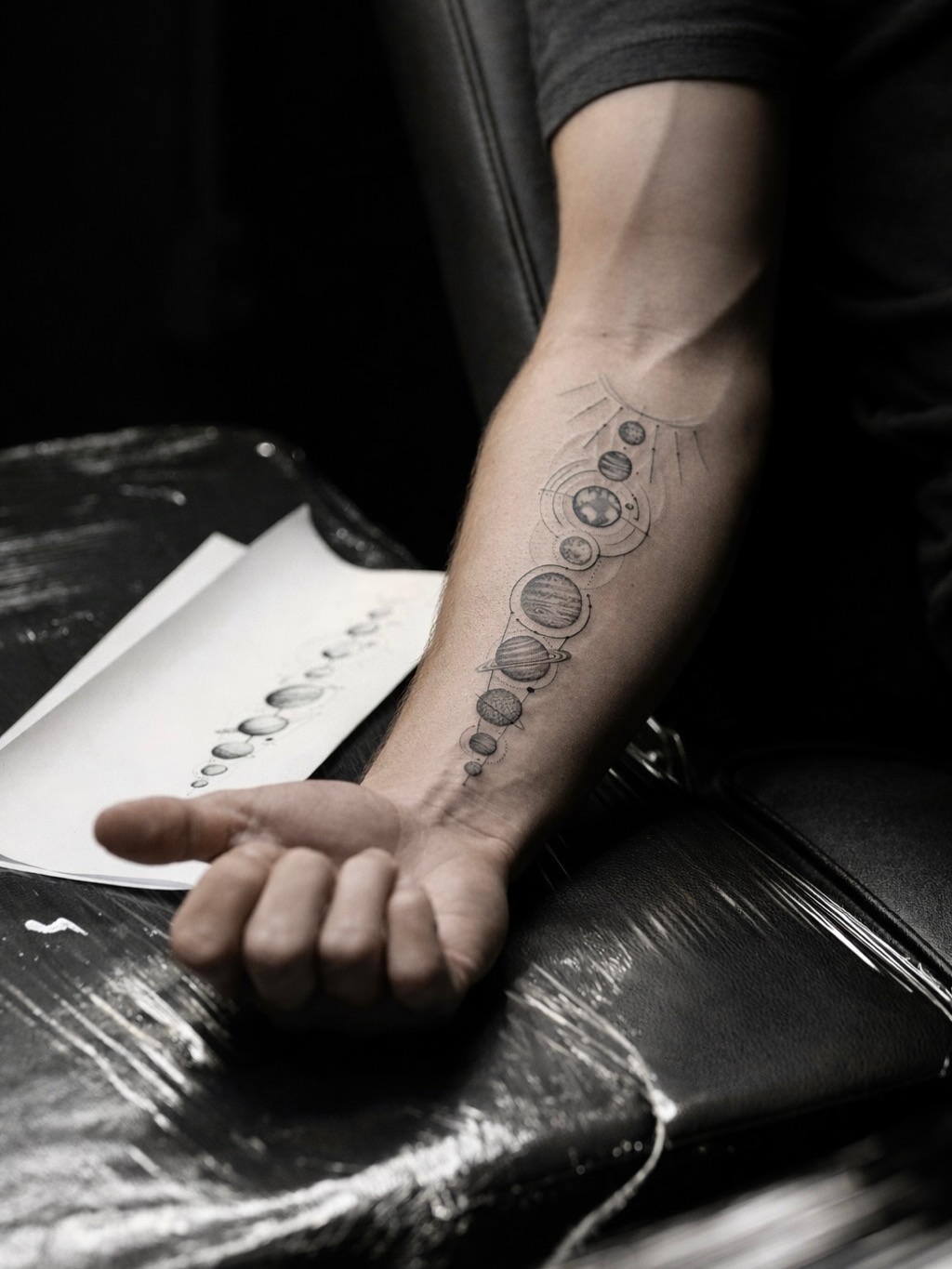 Elegant orbital linework tattoo tracing planets along forearm.