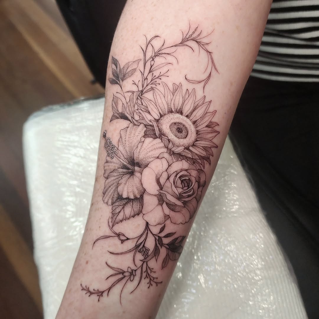 Delicate black-ink floral bouquet with roses, a sunflower, and vines.