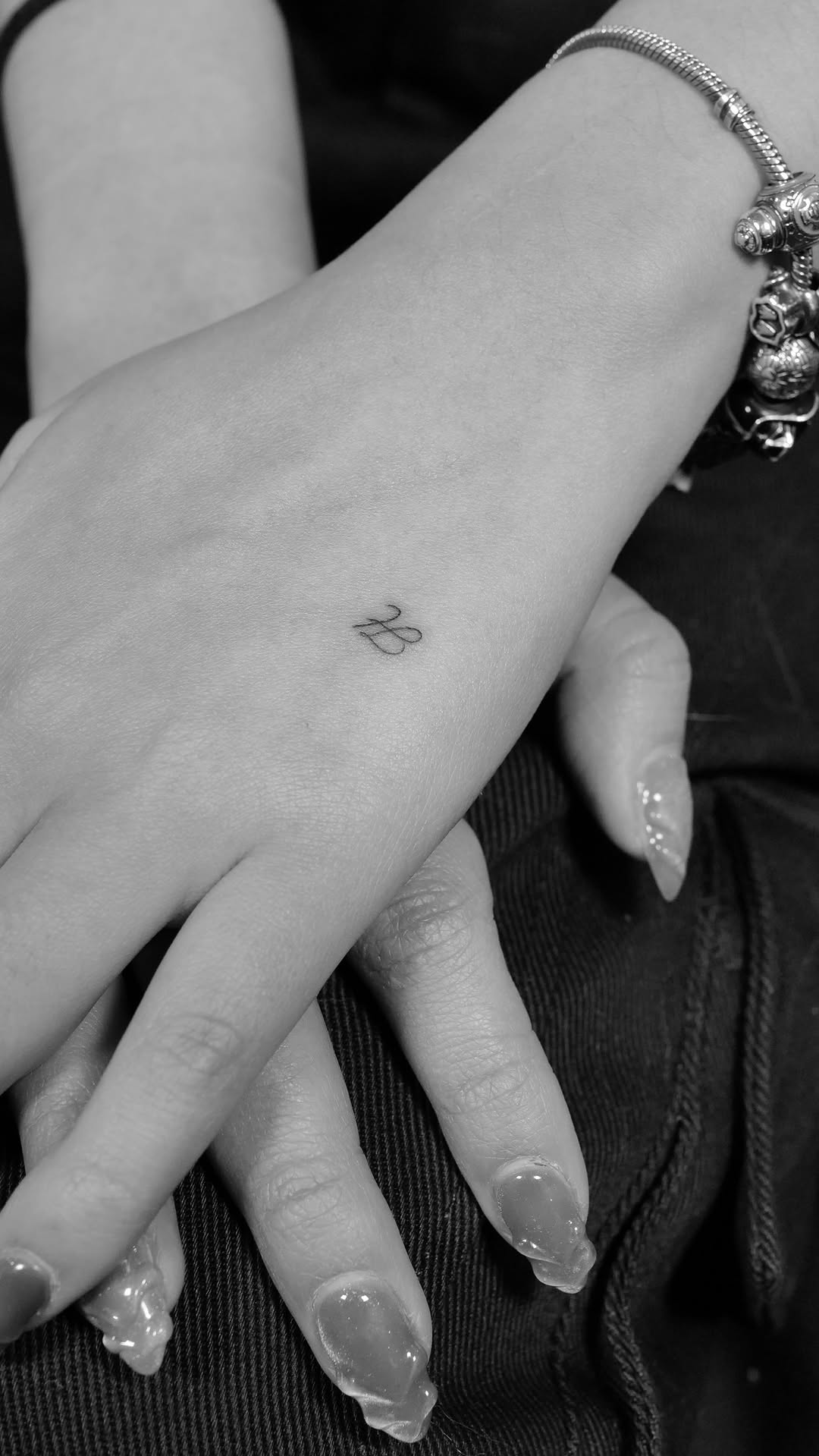 Dainty cursive initial tattoo on the wrist, minimalist