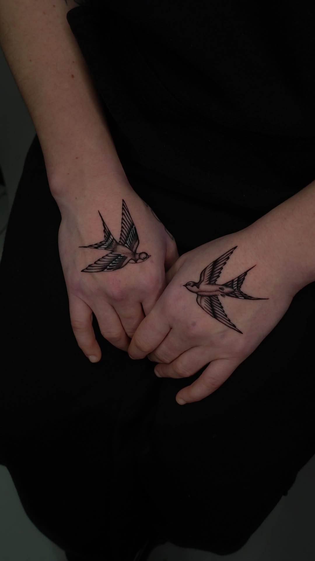 Twin fine-line swallows soaring across the hands