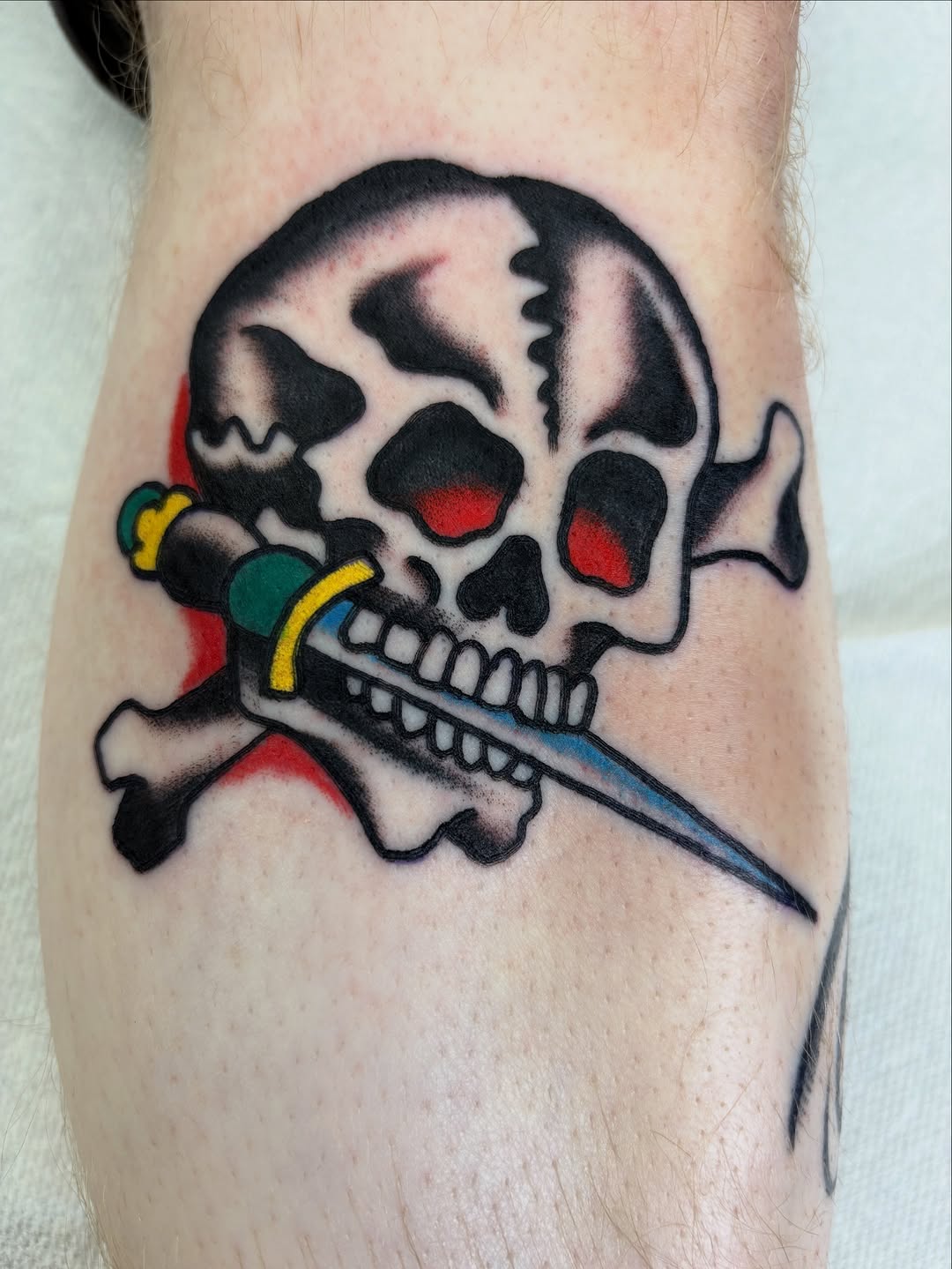 Bold traditional skull with dagger through teeth.