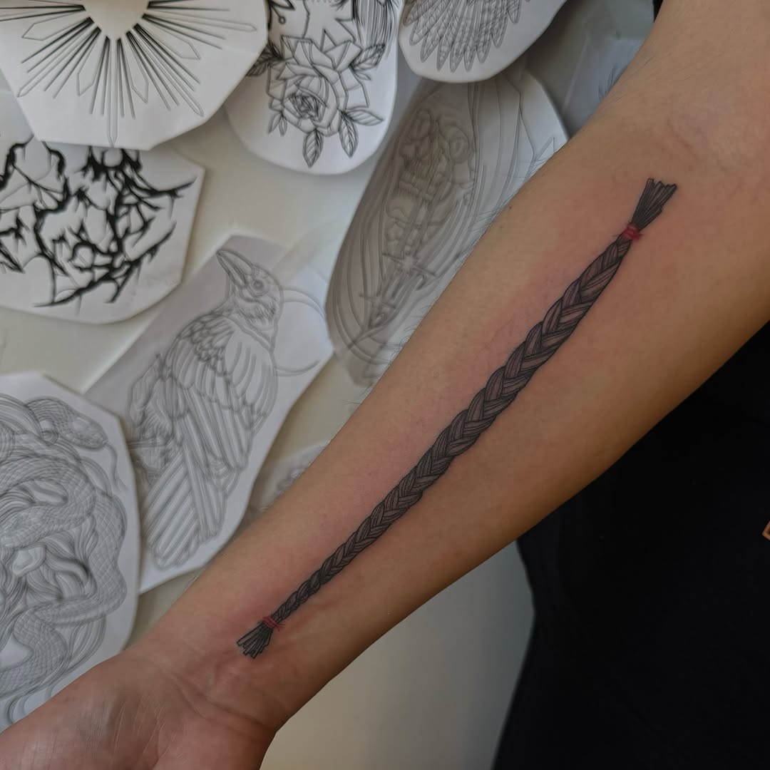 Bold black braided rope armband with tassel tips.