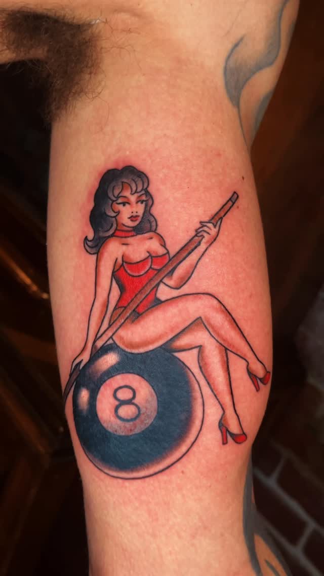Pin-up girl perched on an eight-ball cue.