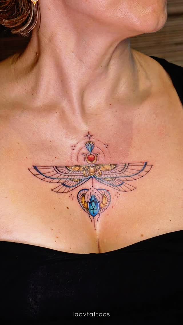 Delicate geometric winged-sun tattoo with jewel-toned accents