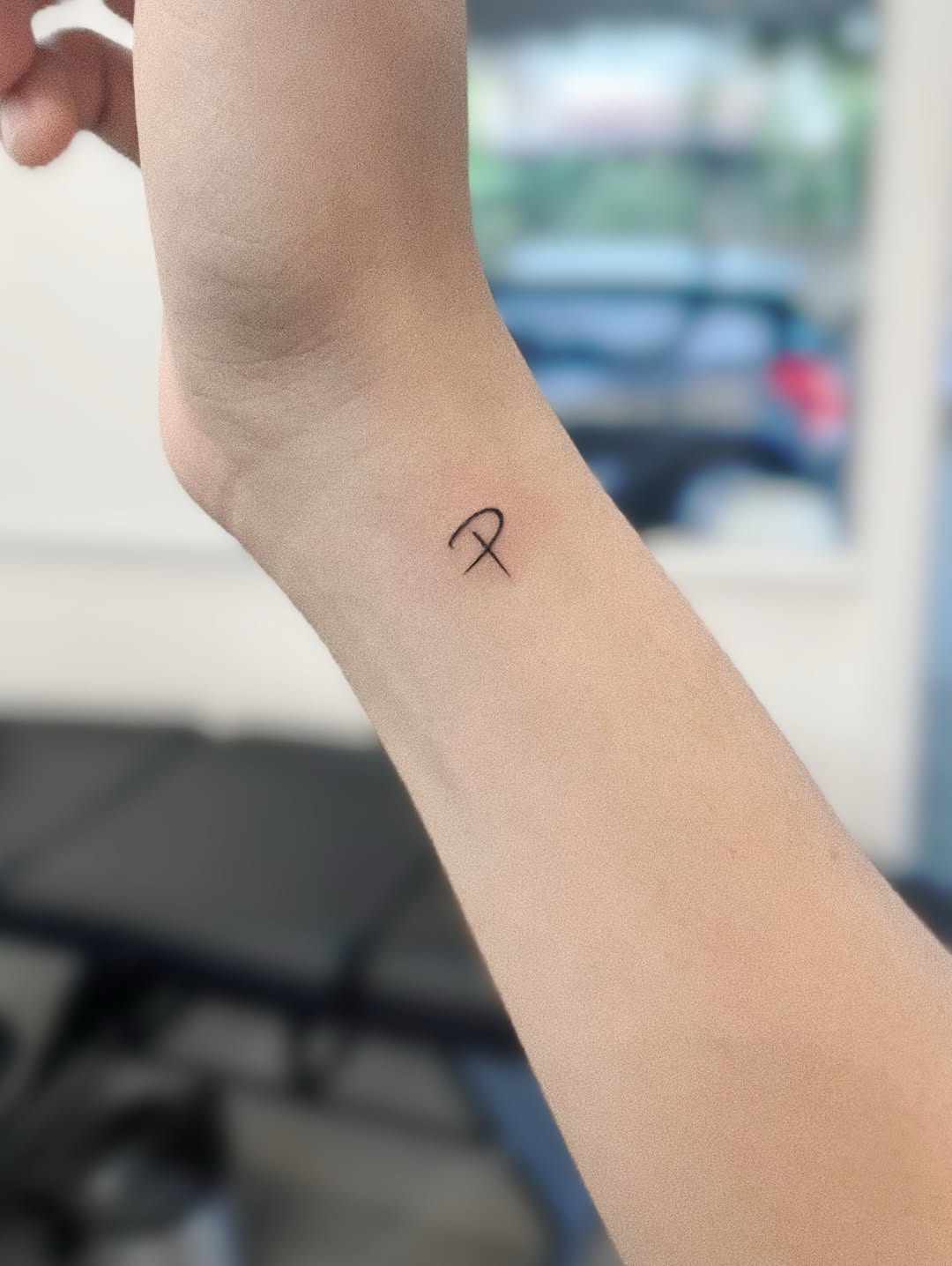 Minimalist single-line loop tattoo on inner forearm
