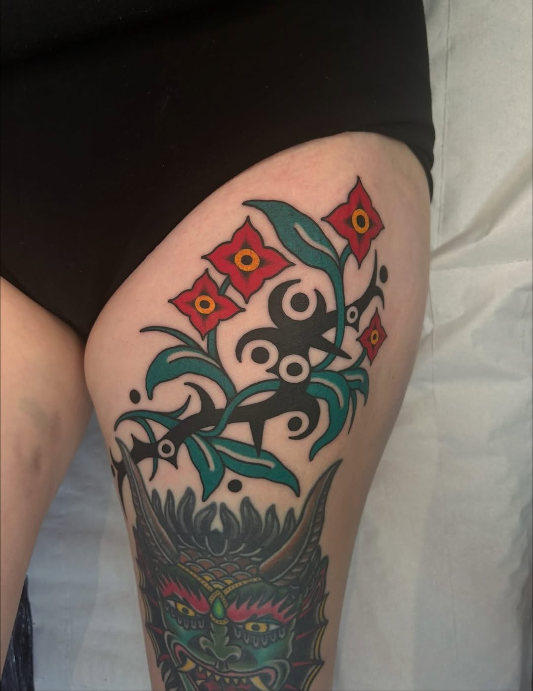 Bold neo-traditional leg piece with floral vines and oni.
