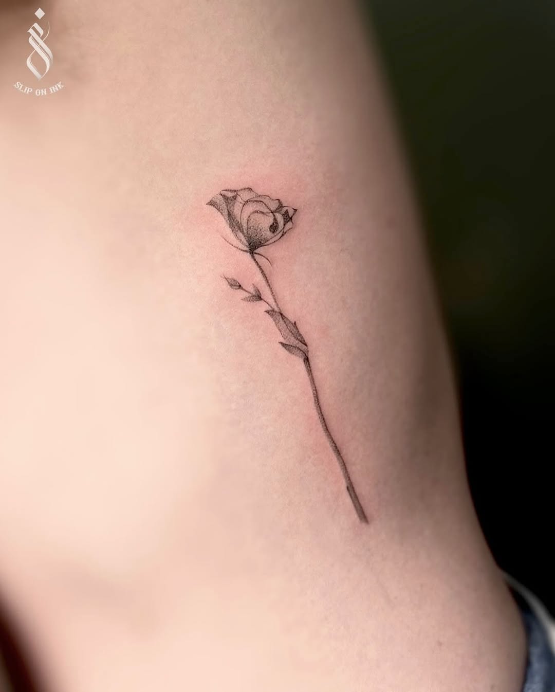 Delicate minimalist rose on slender forearm, fine-line