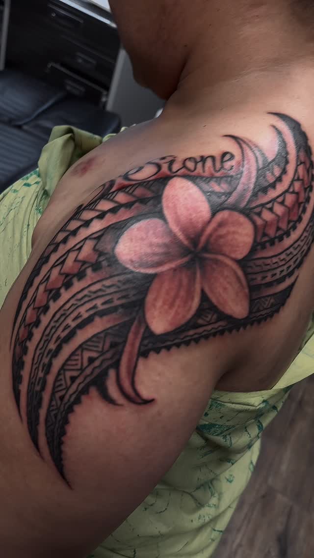 Bold blackwork tribal-geometric sleeve framing a frangipani