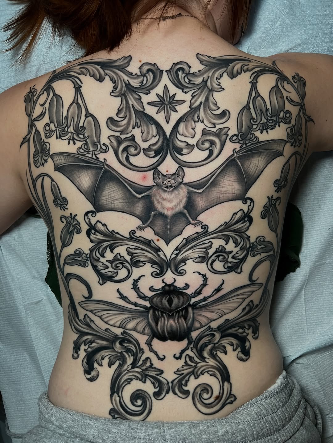 Intricate blackwork back piece with bat and ornamental scrolls