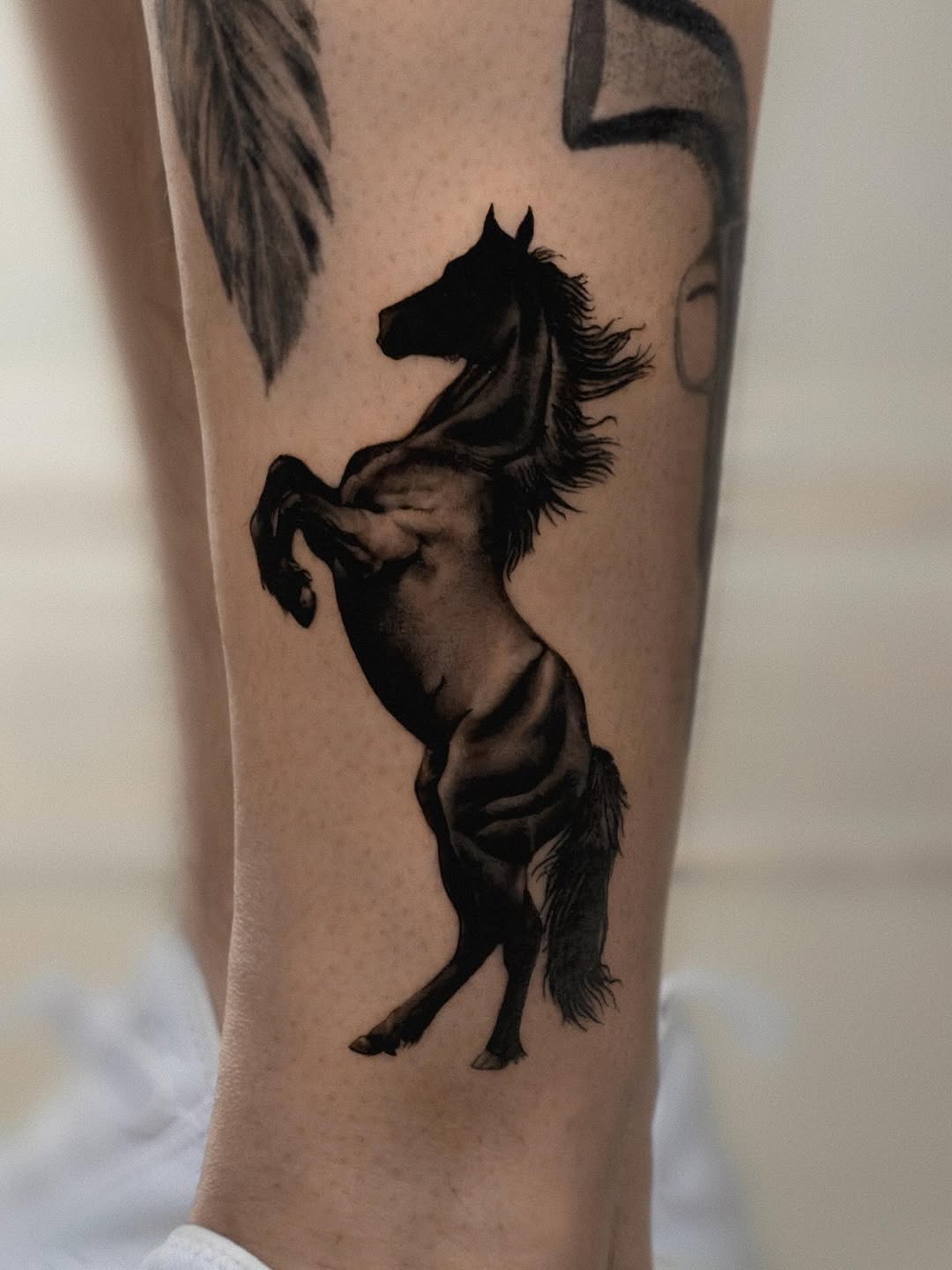 Black horse tattoo on leg