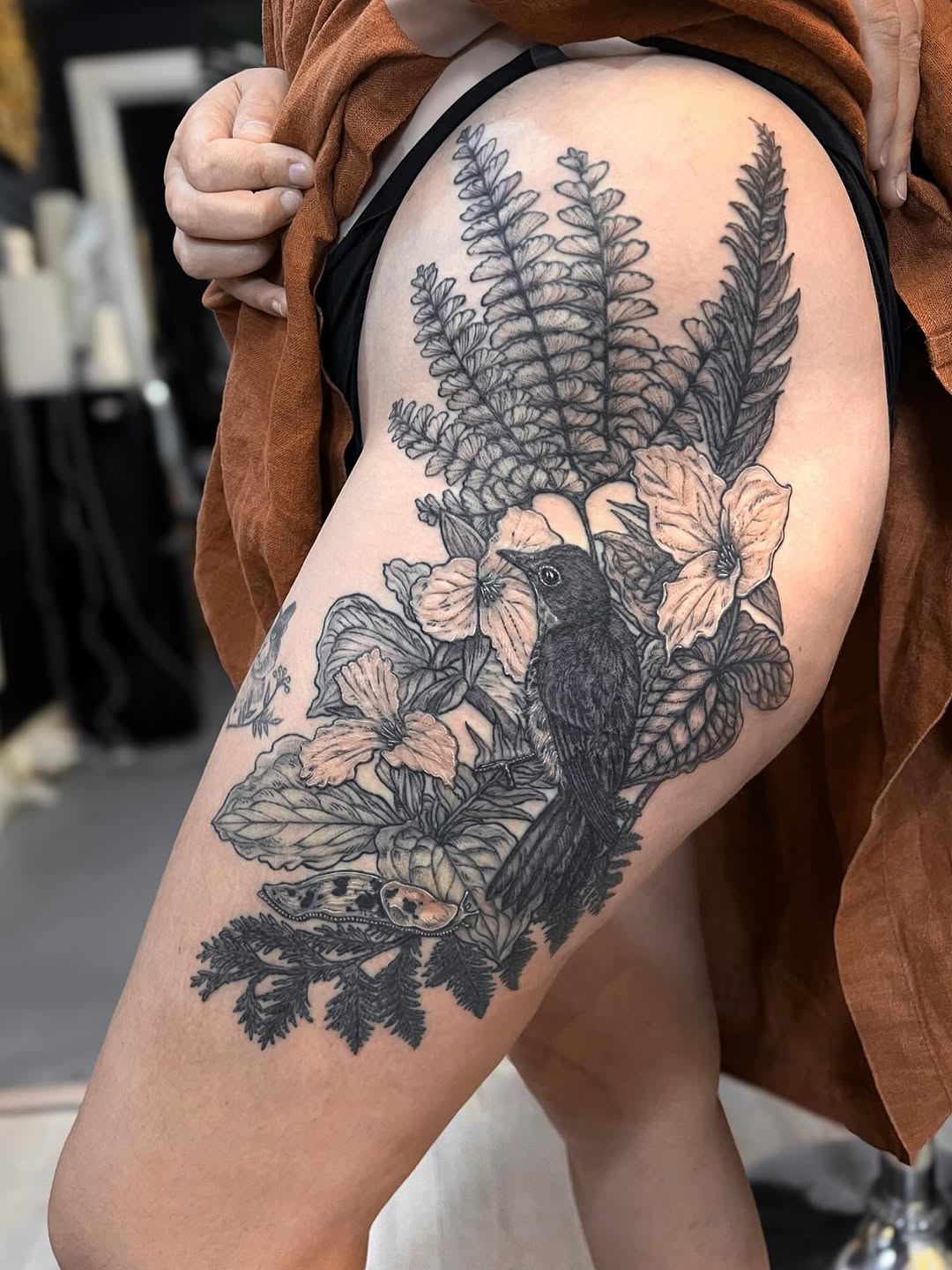 Monochrome thrush among lush ferns and tropical blooms.