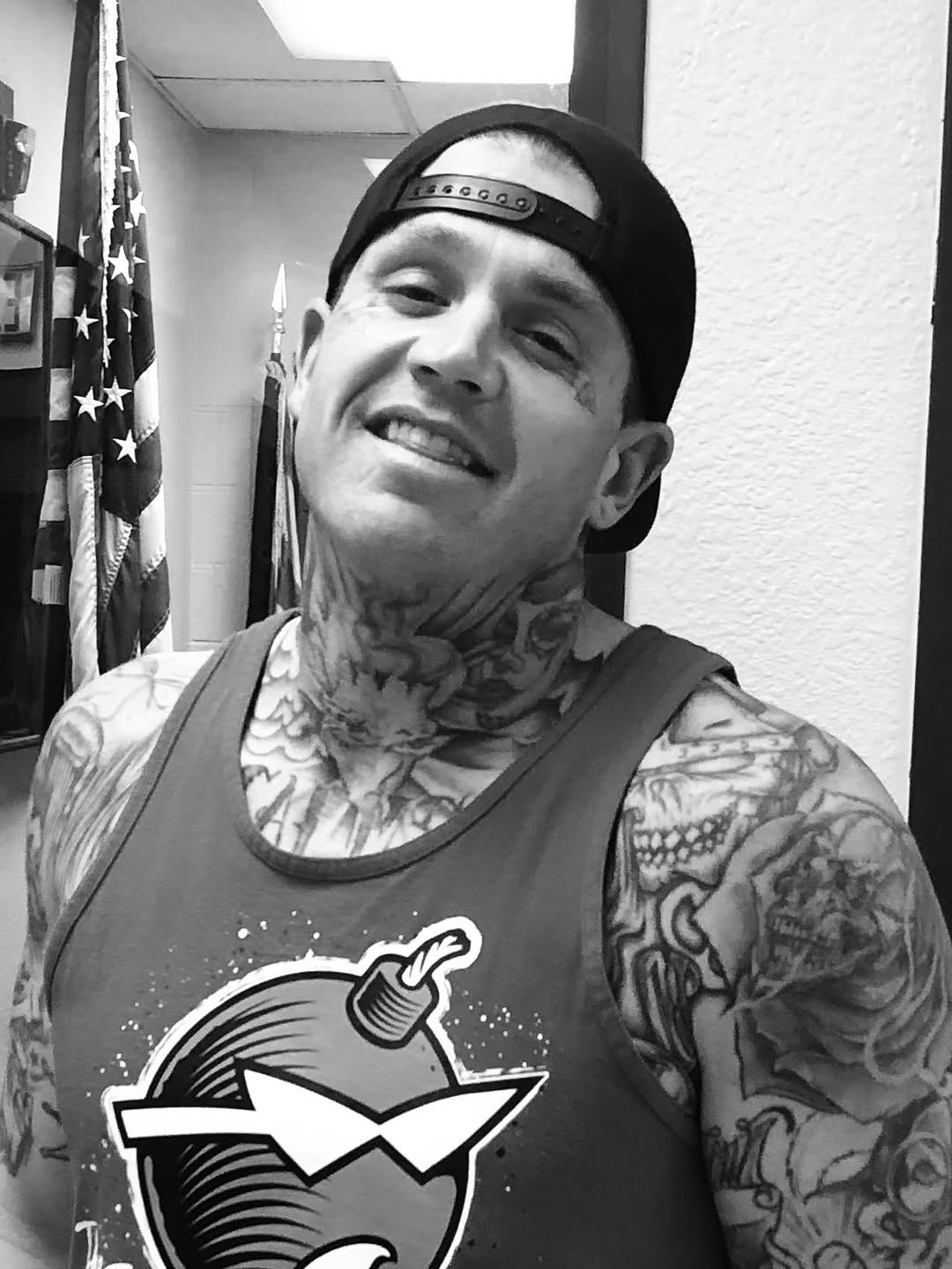 Dense black-and-gray neck and sleeve tattoos, bold shading.
