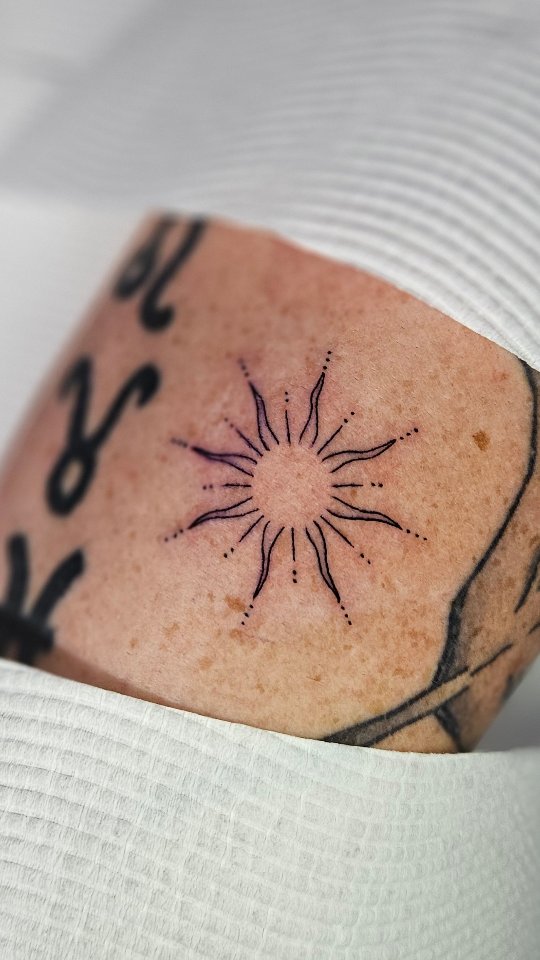 Tiny sunburst with delicate radiating lines and dots