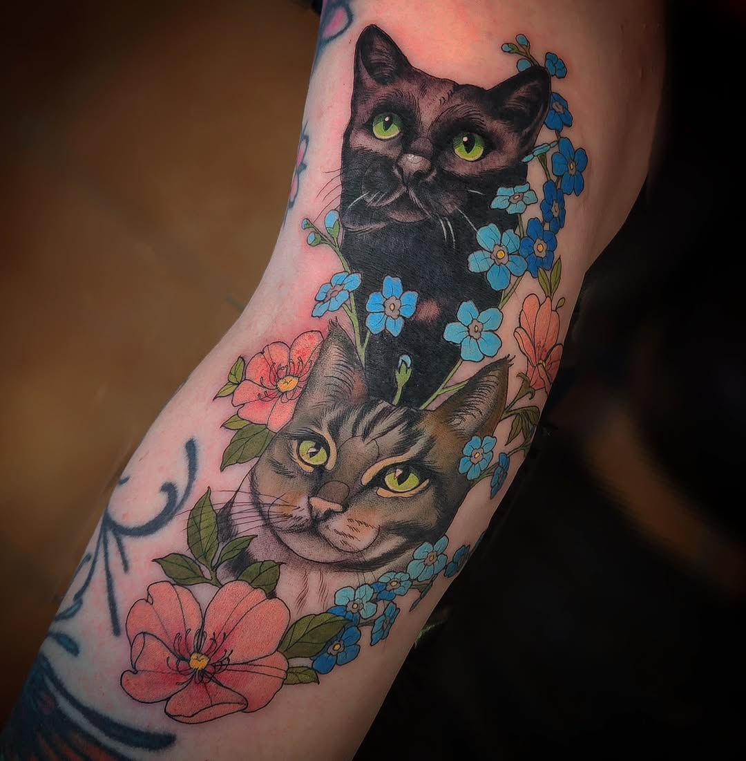 Two-cat portrait framed by vibrant blue blossoms.