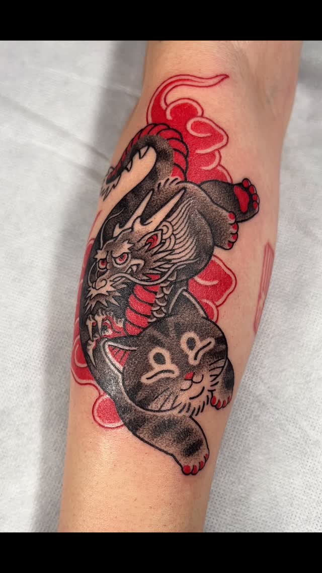 Bold traditional dragon coils around a playful cat, red clouds
