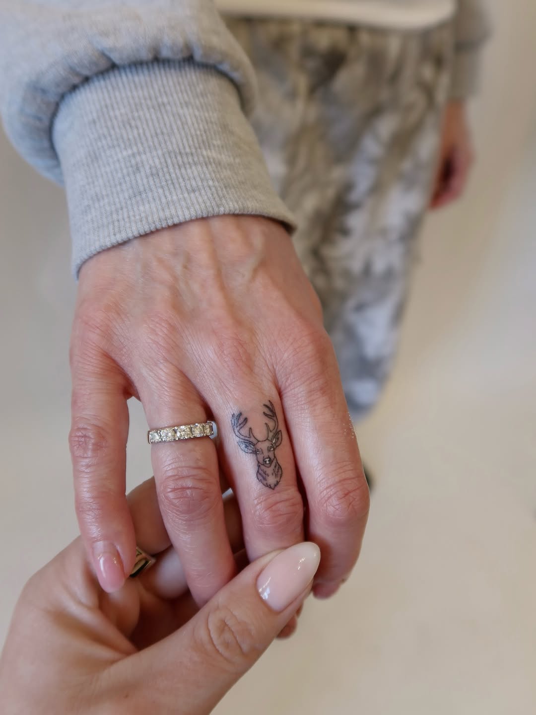 Delicate deer head micro-tattoo on finger