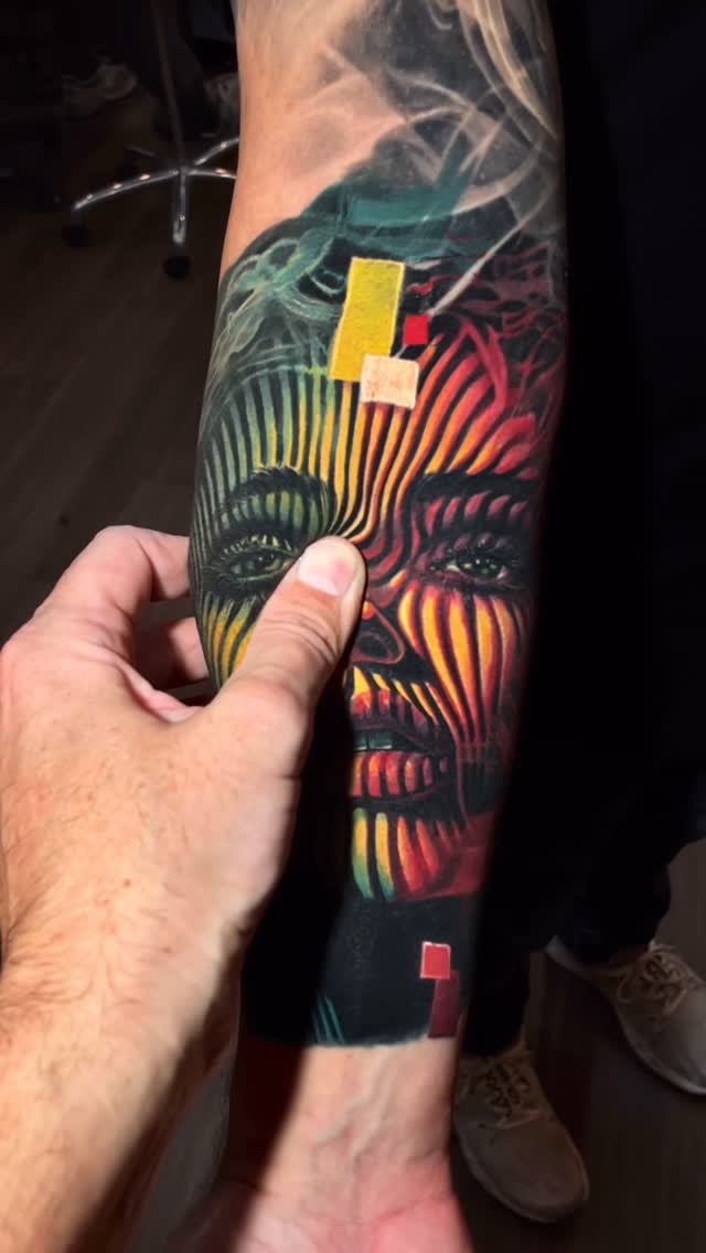 Vivid neon-striped portrait on forearm with geometric shading