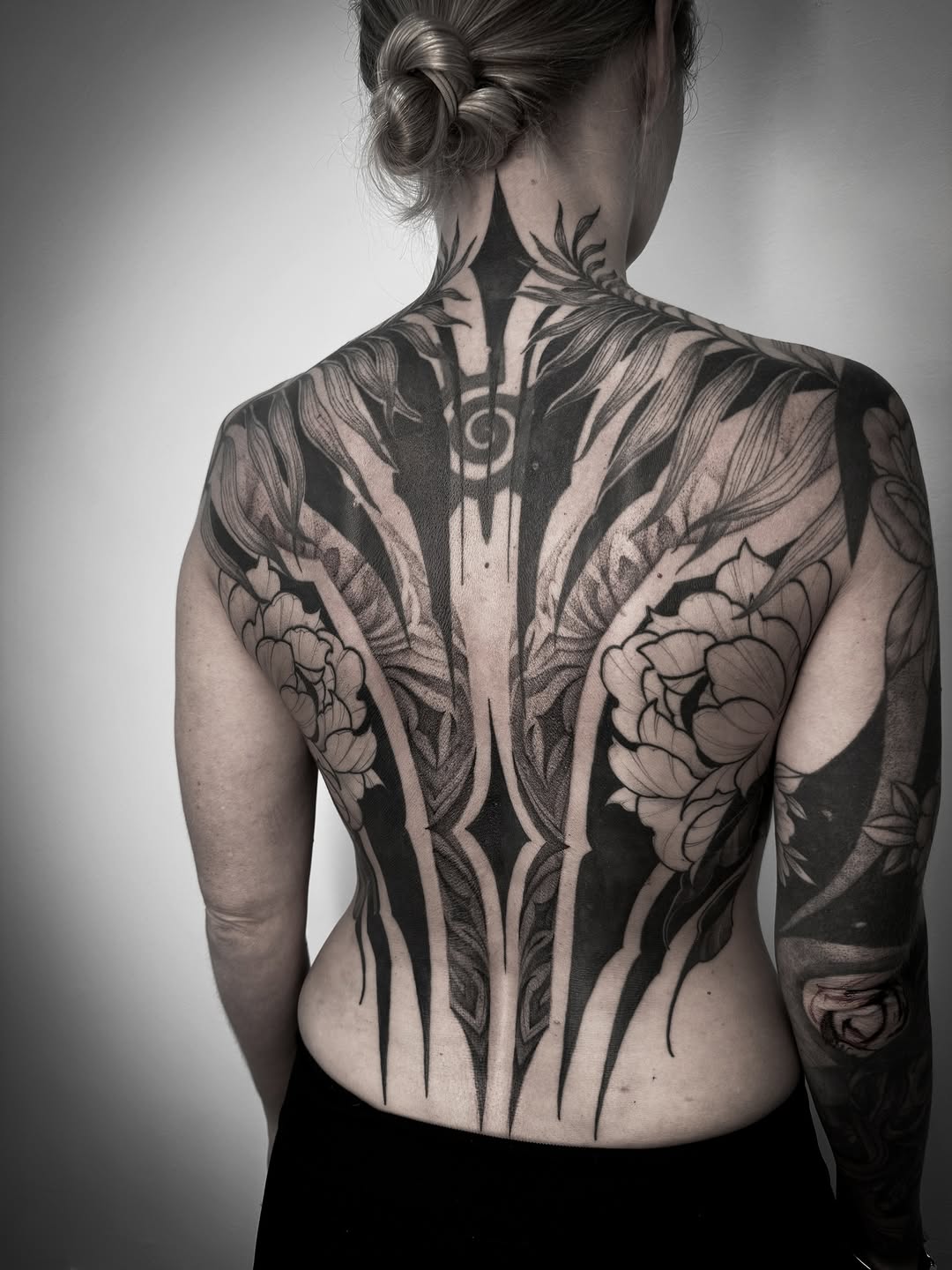Intricate blackwork backpiece with bold geometric vines and peonies.