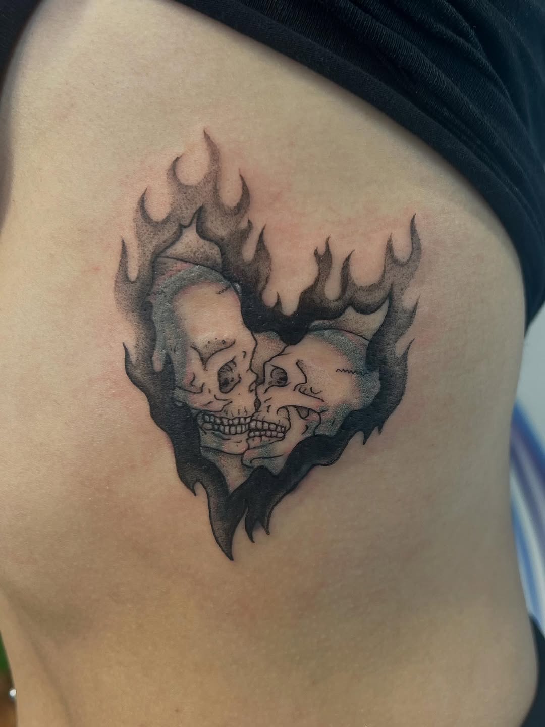 Fiery heart frame with twin skulls in bold blackwork