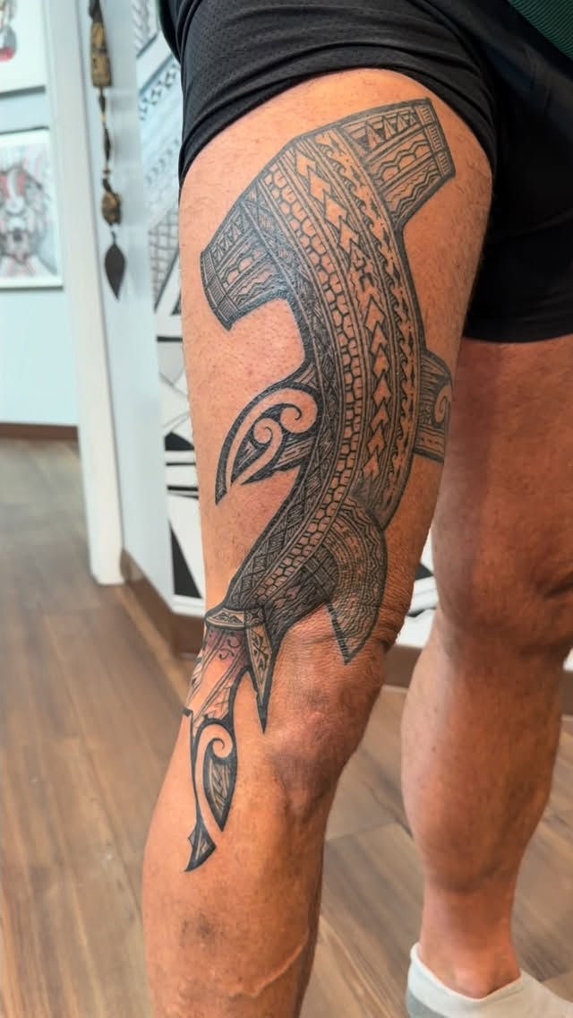 Polynesian-style hammerhead shark wrap with heavy blackwork detailing.