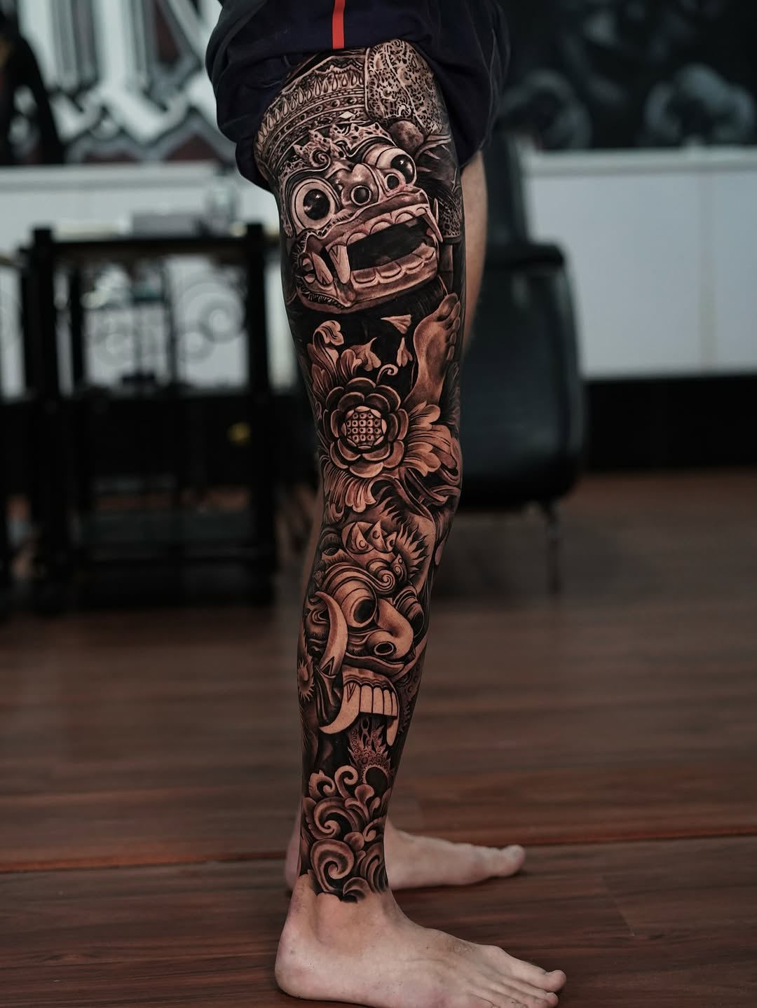 Intricate black-and-gray leg sleeve with demon mask and florals
